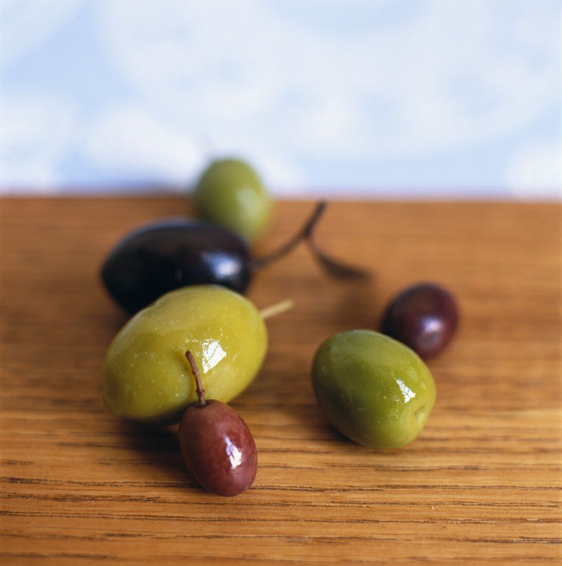 Green and black olives on wooden table