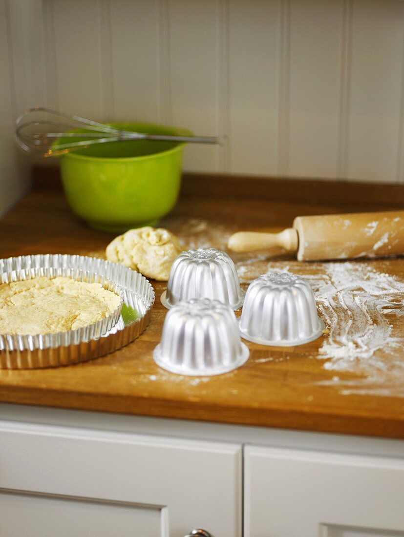 Dough, baking tins and baking utensils in kitchen