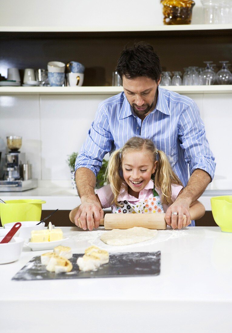 Father and daughter rolling out pastry