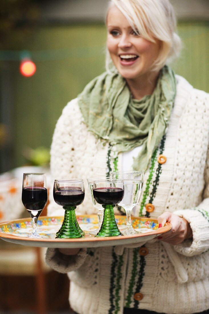 Frau serviert Tablett mit Weingläsern