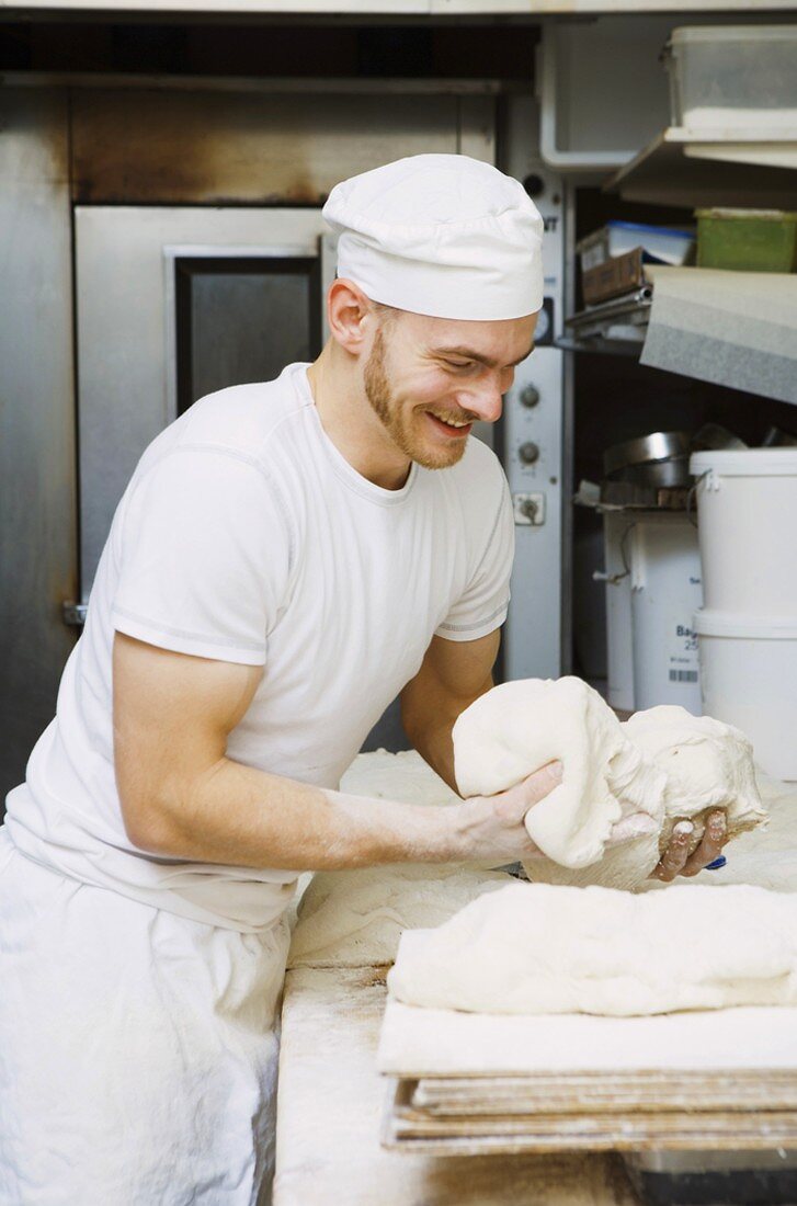 Baker shaping dough in bakery