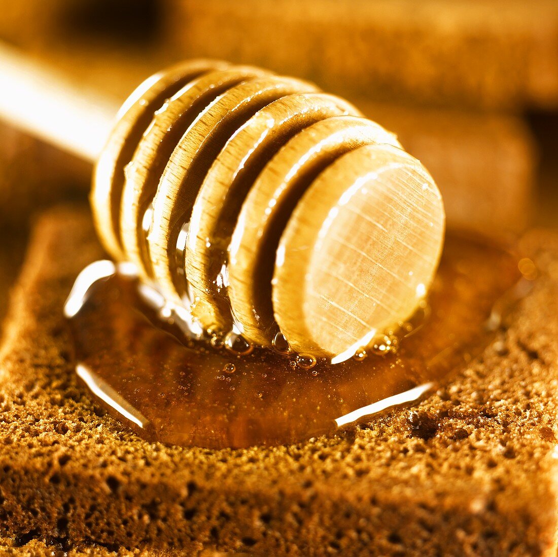 Honey dipper and honey on wholemeal bread