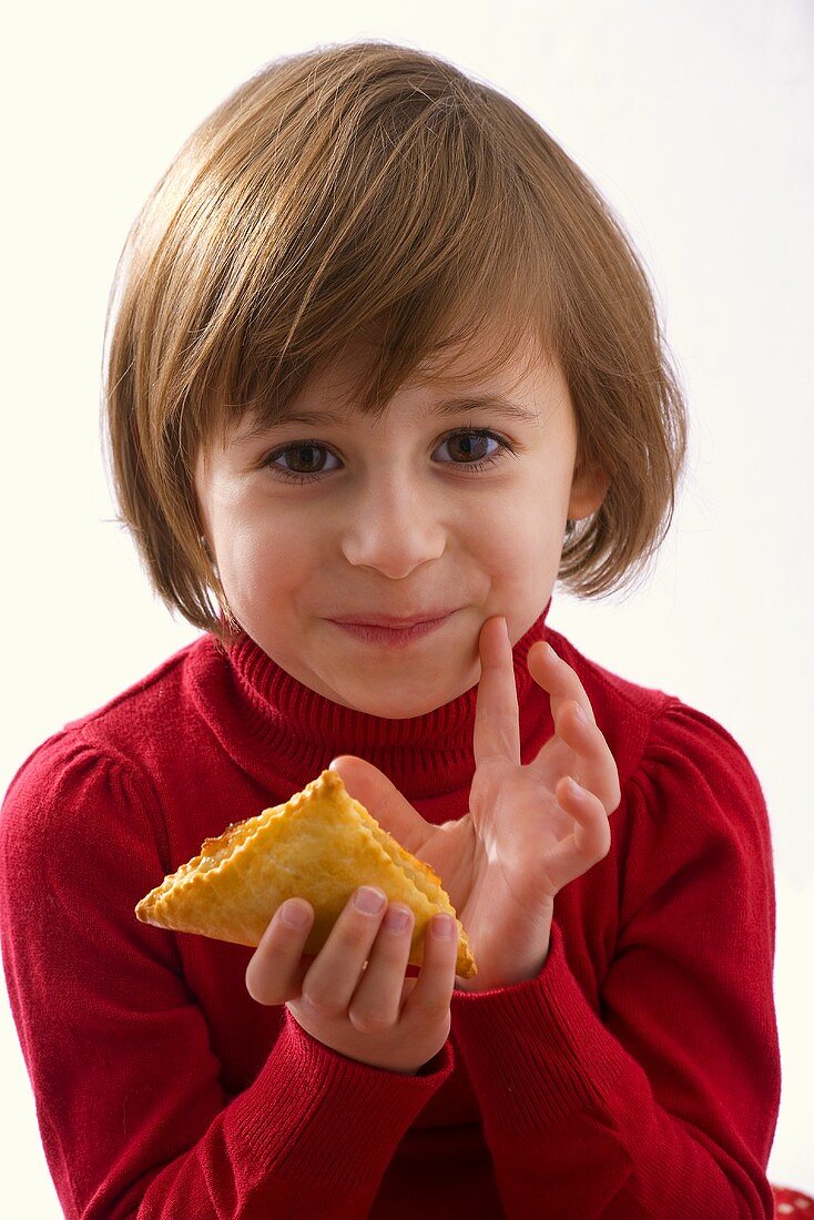 Little girl holding a puff pastry in her hand