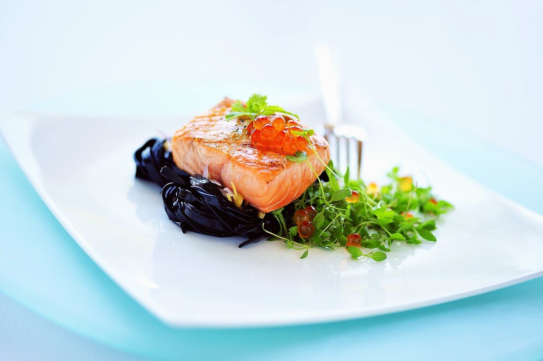 Gebratener Lachs auf schwarzen Tagliatelle mit Baby-Basilikum