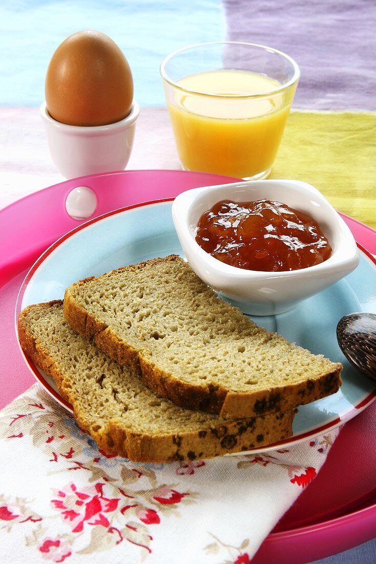Bread, marmalade, orange juice and egg for breakfast