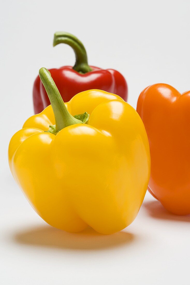 Yellow pepper with a red and an orange pepper in background