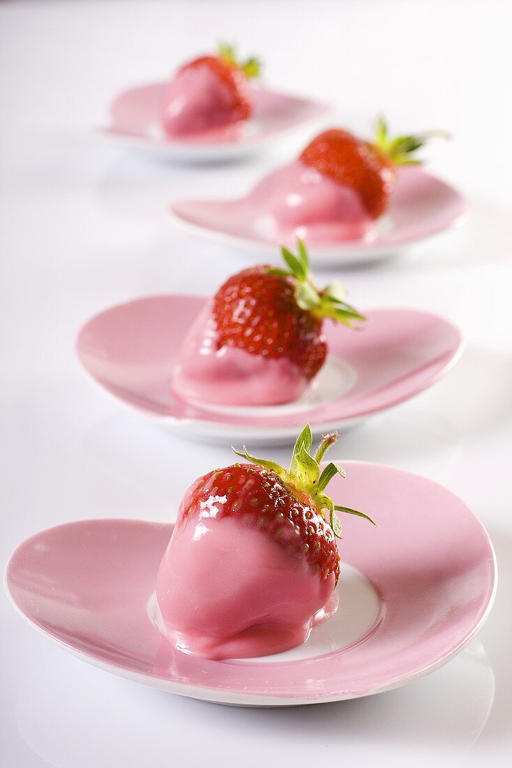Erdbeeren mit rosa Glasur auf herzförmigen Tellern