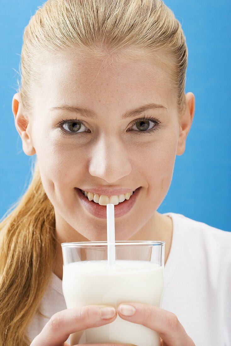 Junge Frau trinkt Milch mit Strohhalm