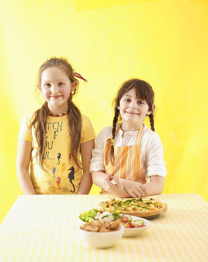 Two girls standing by kitchen table