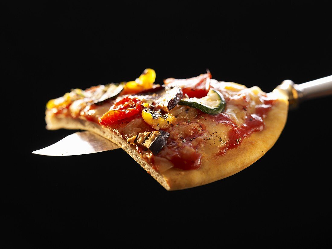 A slice of grilled vegetable pizza on knife
