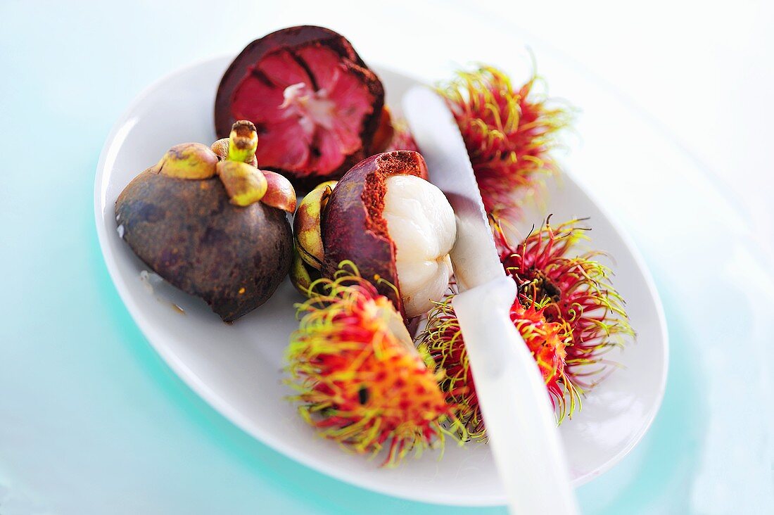 Mangosteen, partly peeled, and rambutans