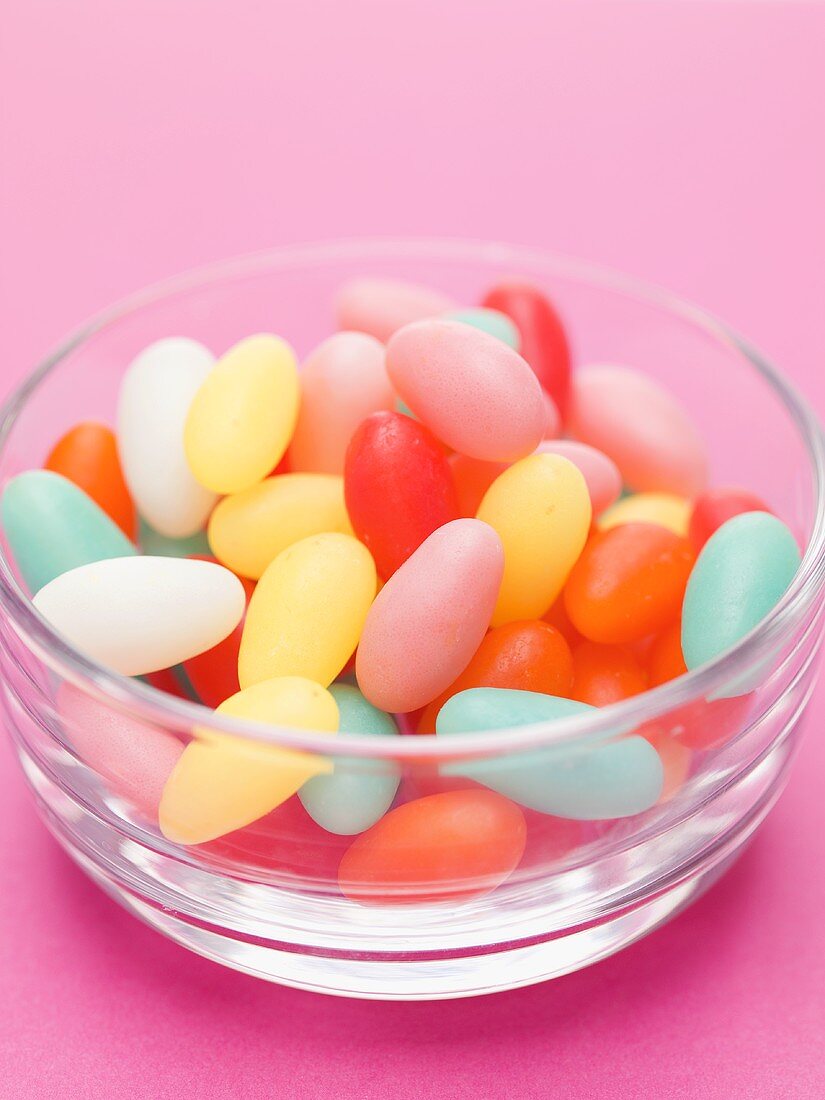 Coloured sugar eggs in glass dish, pink background