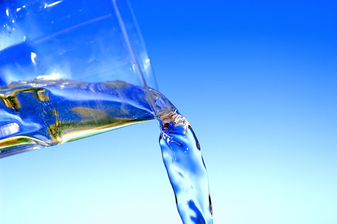 Wasser aus einem Trinkglas gießen