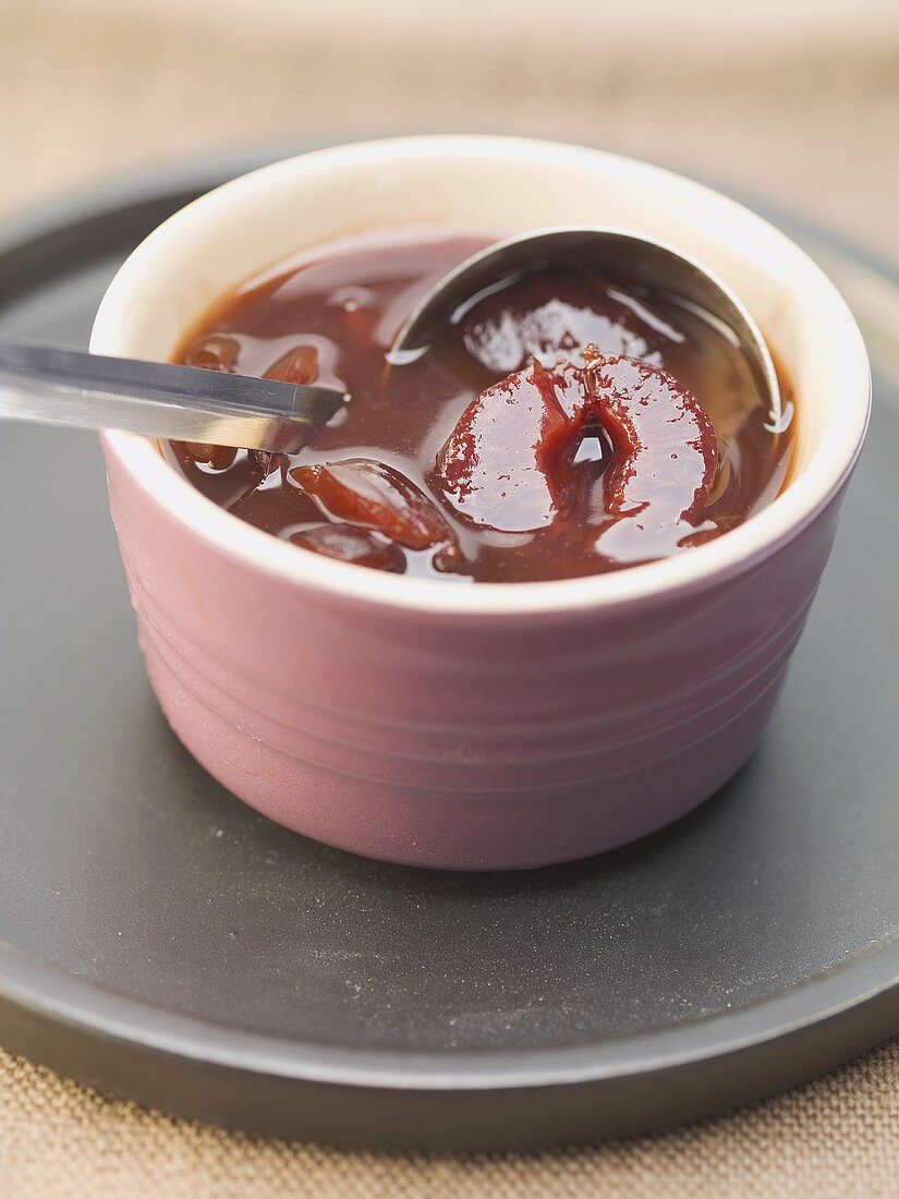 Spiced plum sauce in dish with ladle