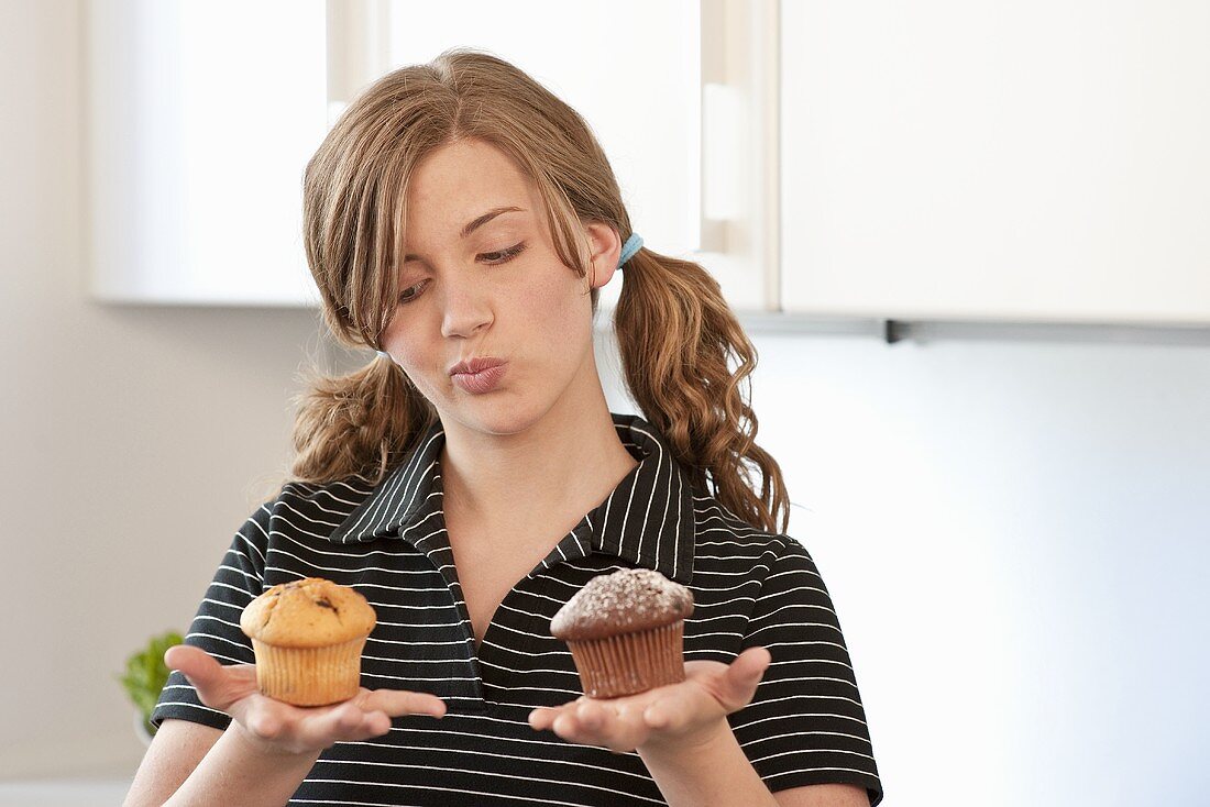 Young woman holding a muffin in each hand