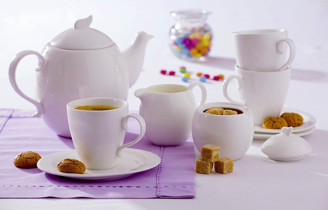 A cup of tea, amaretti, brown sugar and teapot