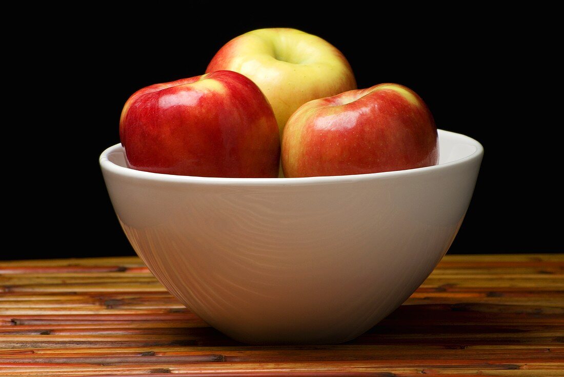 Fresh Apples in a White Bowl on Wood
