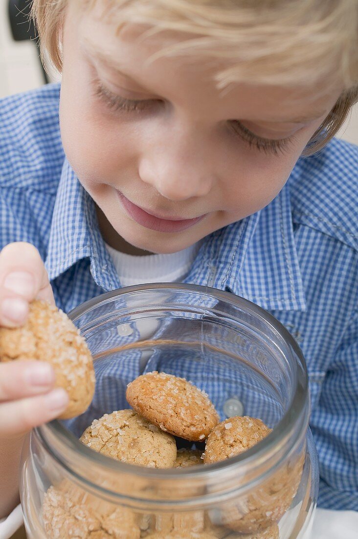 Boy taking biscuit out of storage jar