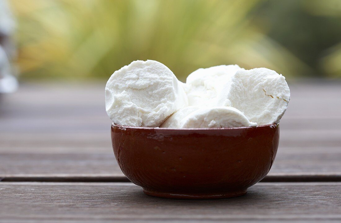 Goat's cheese in bowl on wooden table