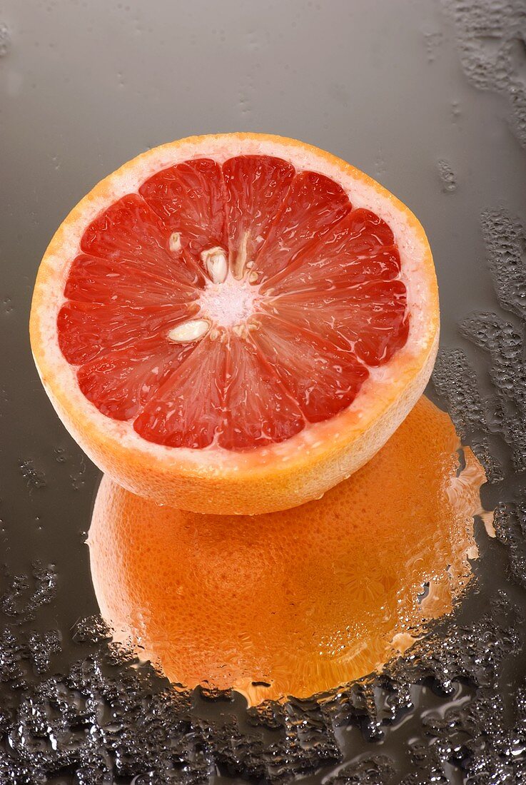 Halbe rosa Grapefruit auf nassem Spiegel
