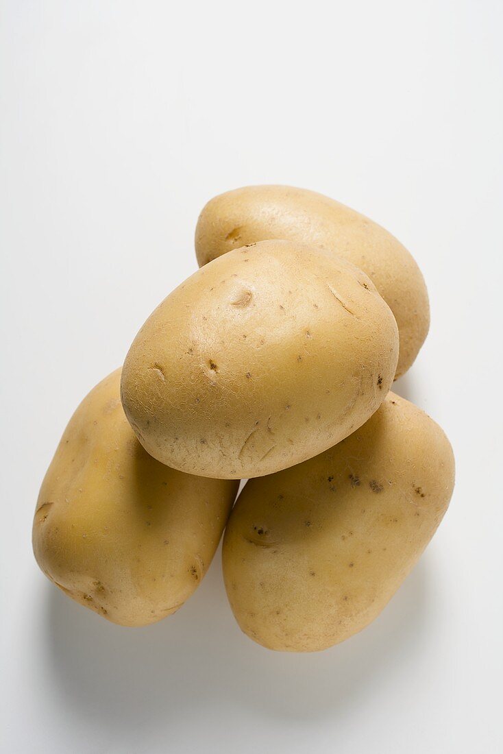 Four Potatoes Stacked on a Weathered Table