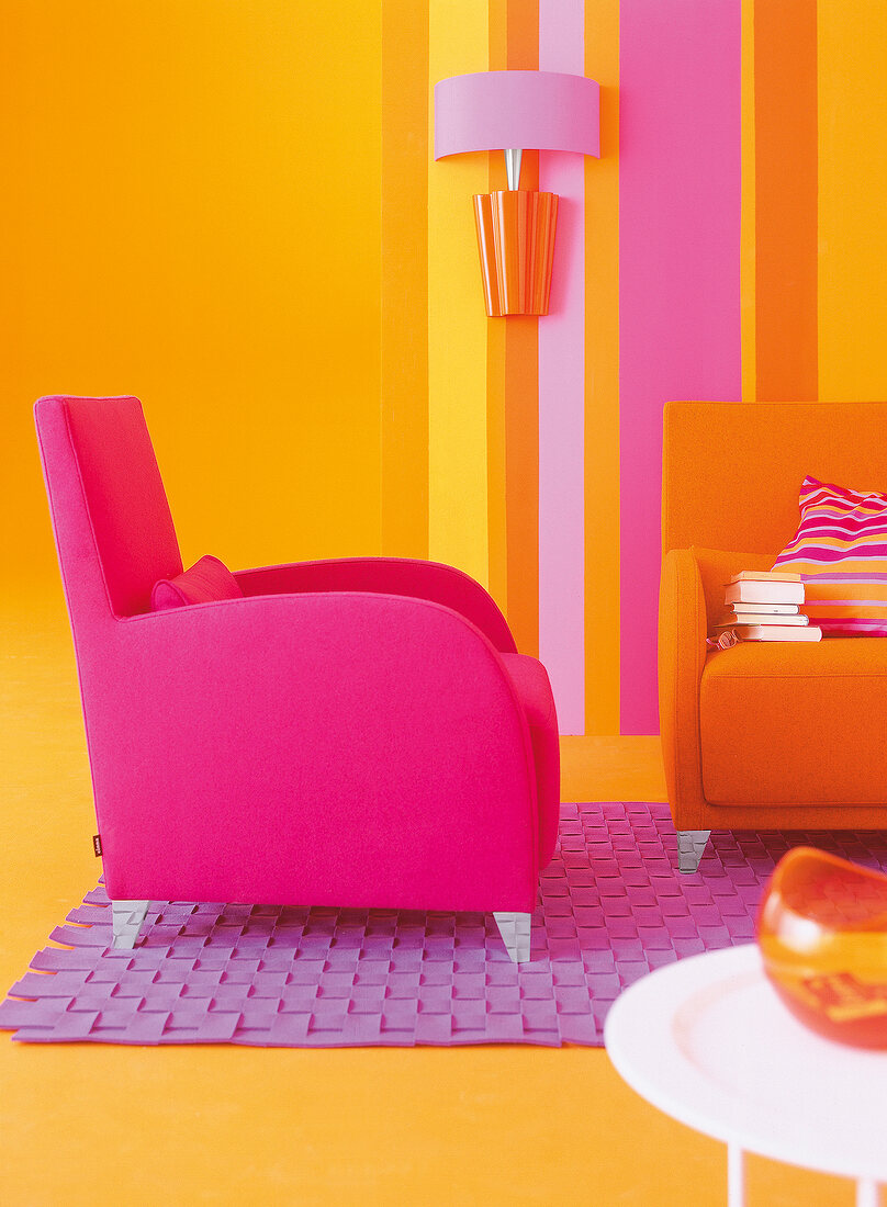 Pink armchair in front of striped wallpaper in living room