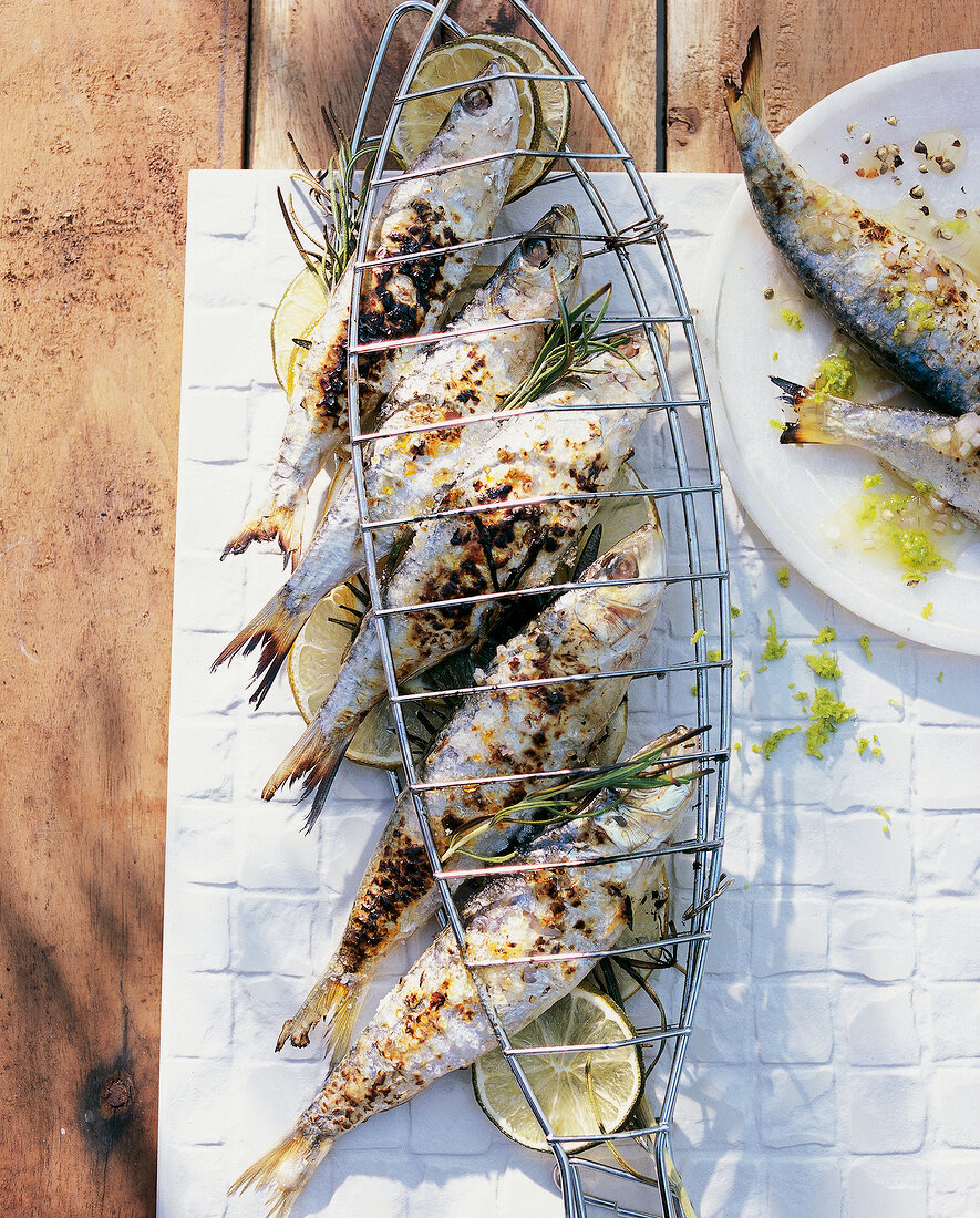 Grilled sardines and lime with rosemary in a grill holder