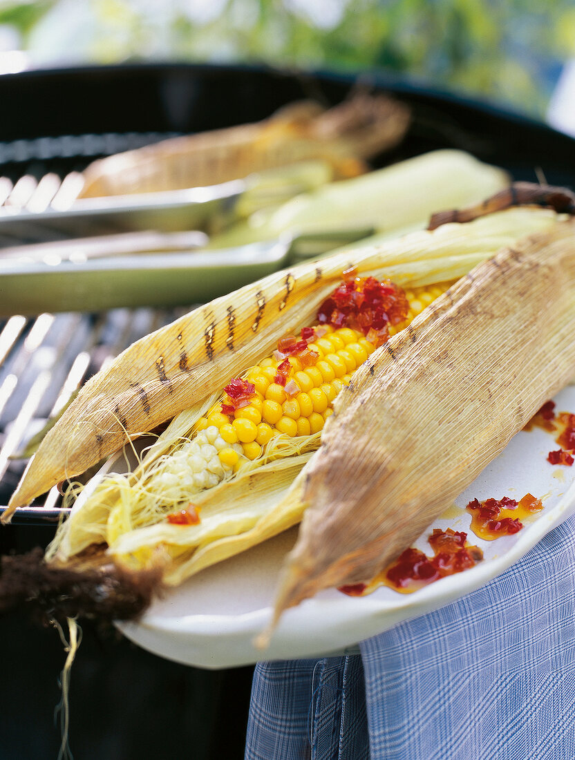 Spicy corn cob on barbecue with sweet and sour pepper sauce