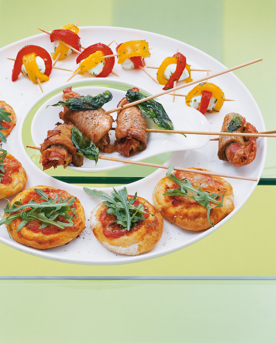 Finger food on white plate against green background