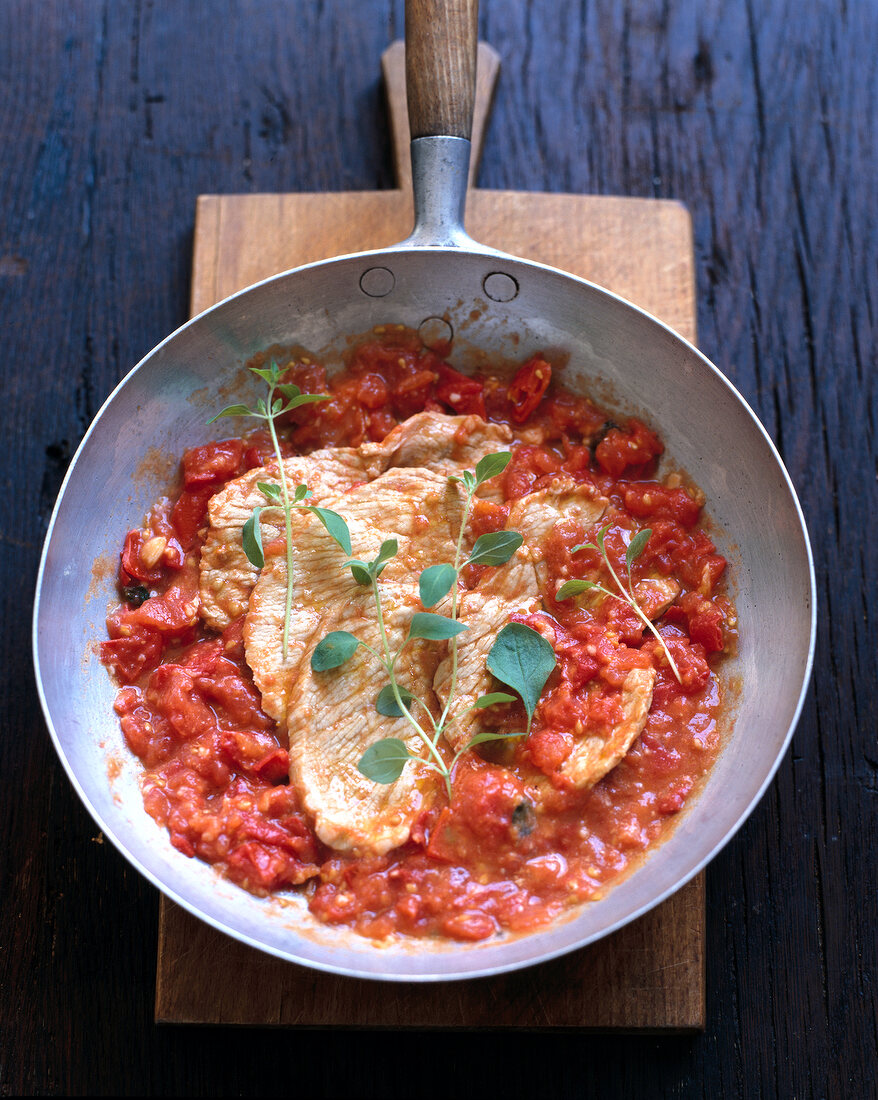 Beef steaks with tomato sauce in pan, overhead view