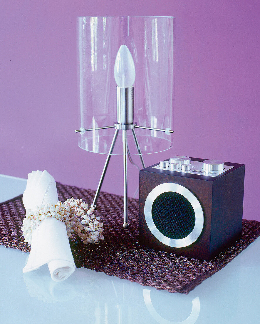 Table with napkins, napkin ring made of shells, radio and transparent lamp