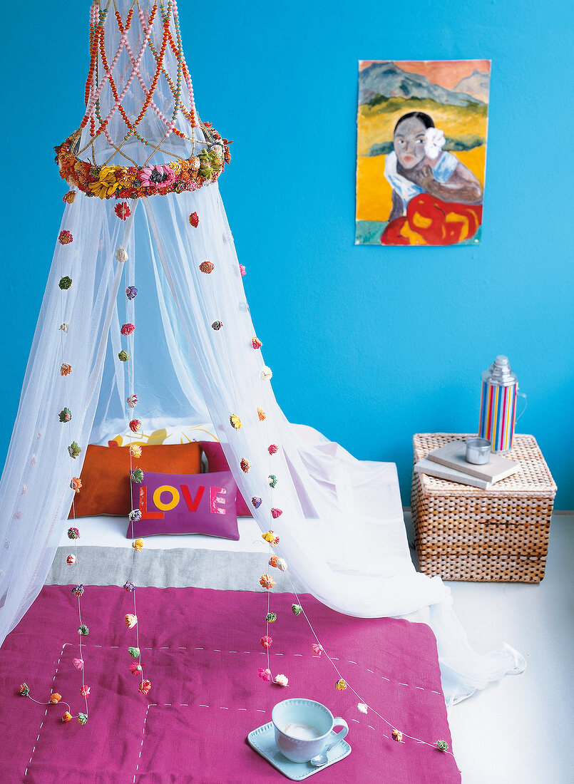Bedroom with white mosquito net decorated with garland and pillows on bed