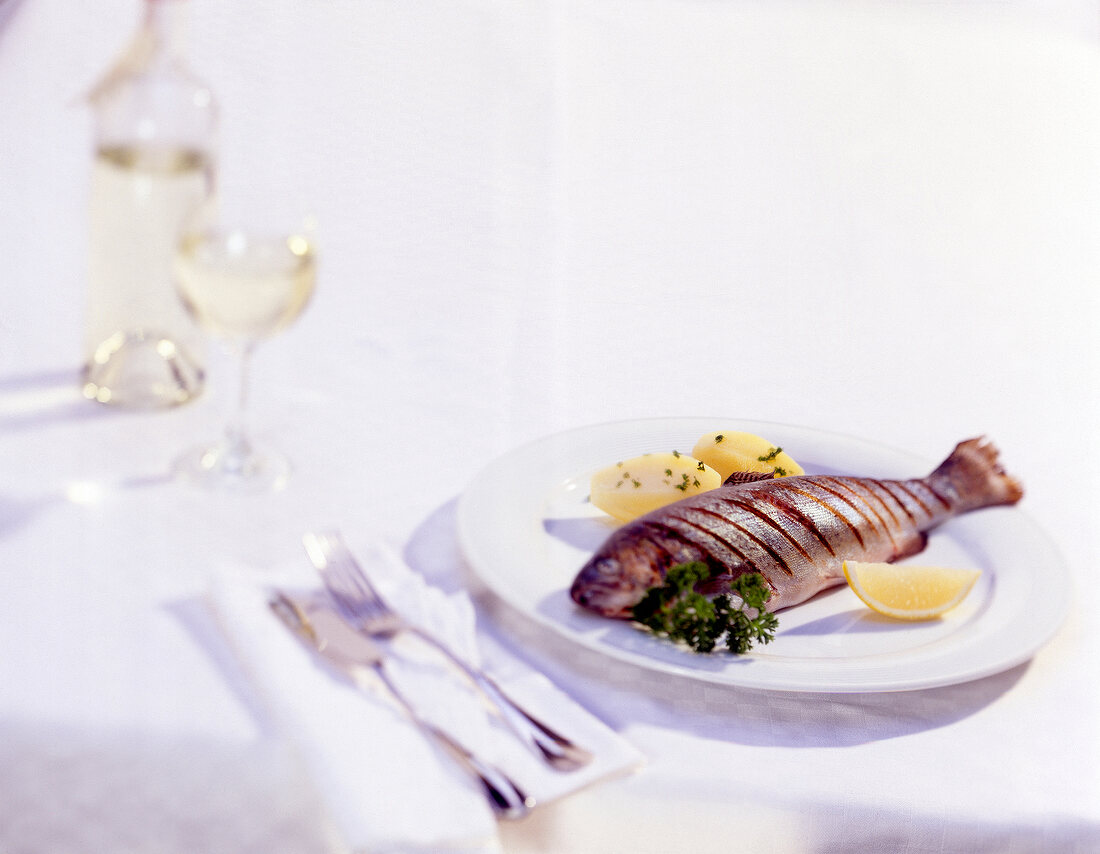 Grilled trout with potatoes and lime on plate