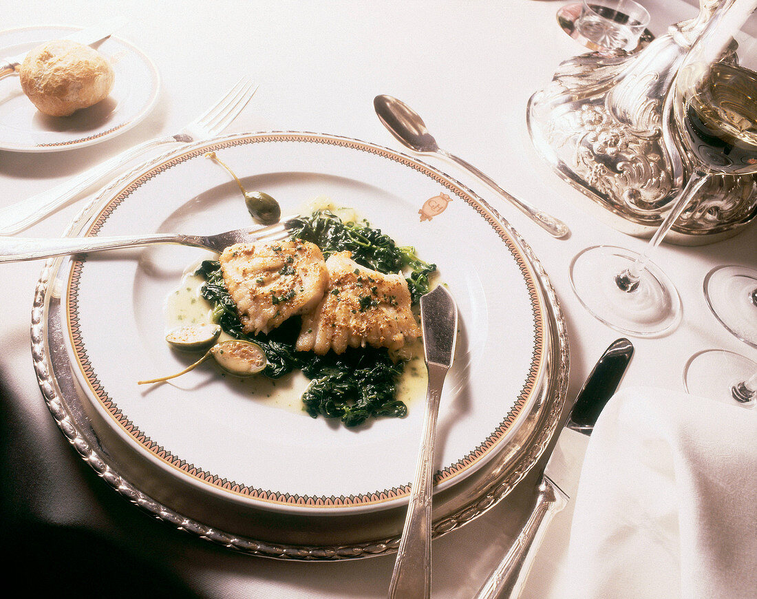 Skate wing on spinach with capers and mustard on plate
