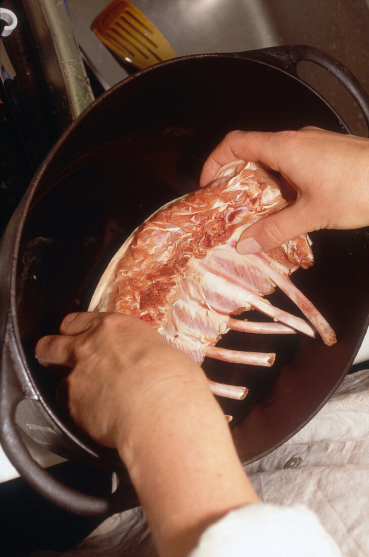Close-up of raw suckling pig being placed in pan