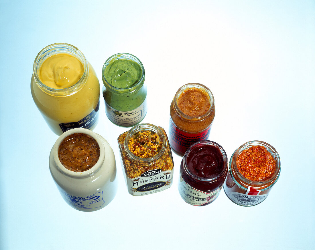 Different types of mustards in jars, overhead view