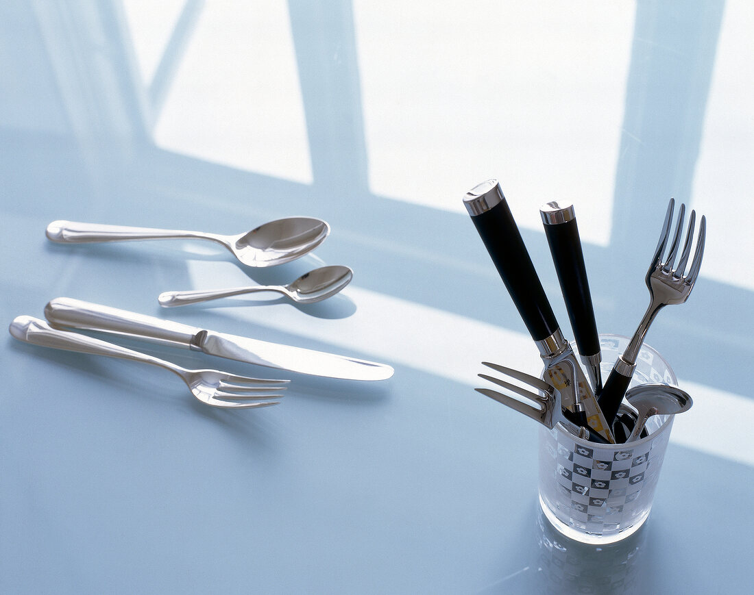 Set of five piece cutlery on window sill and glass