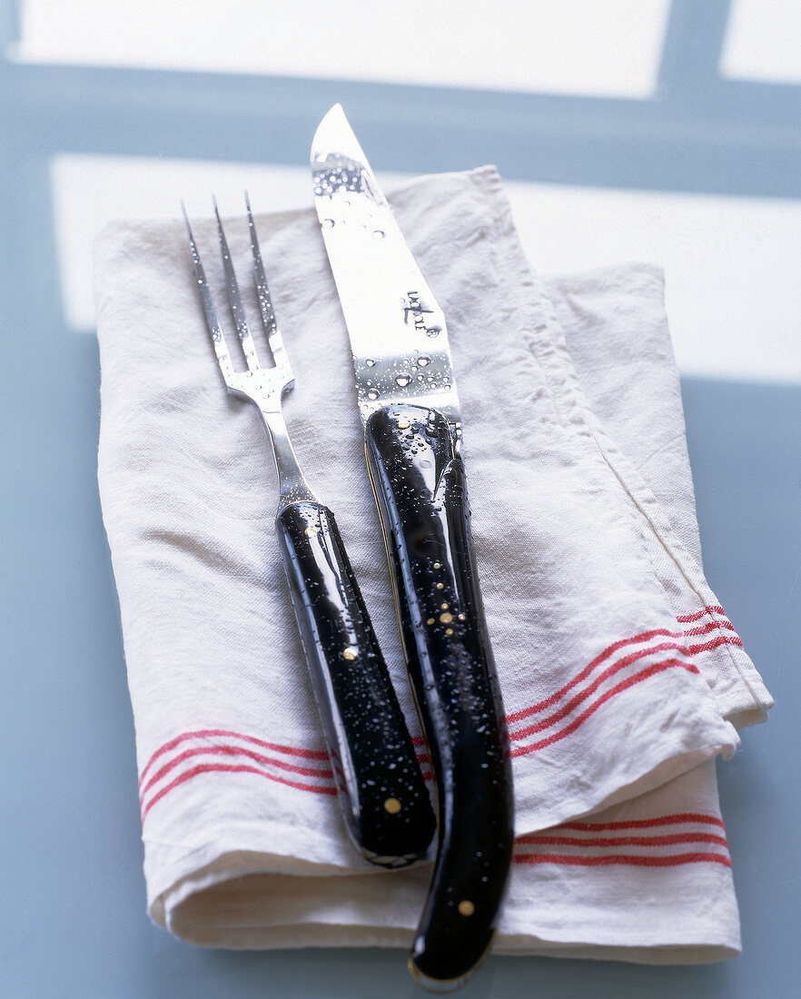 Close-up of carving knife and fork placed on napkin