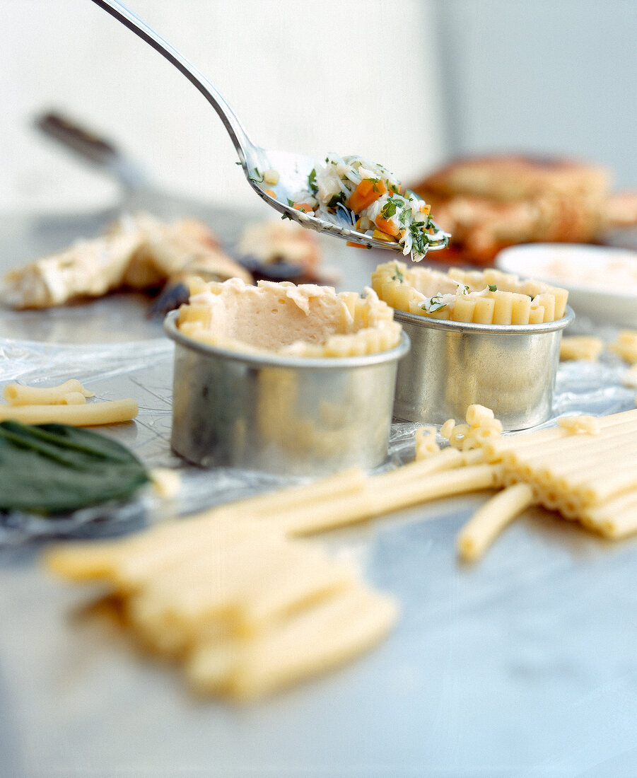 Macaroni timbale being prepared by filling crab stuffing