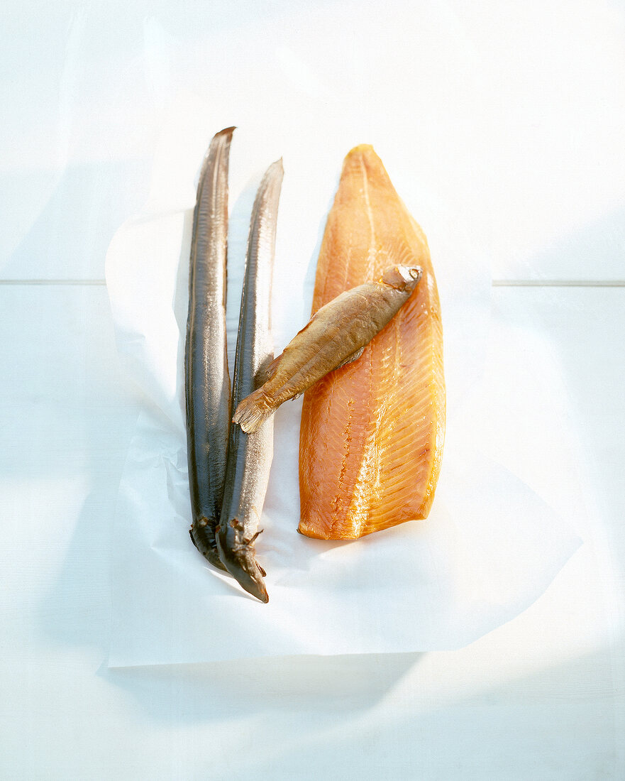 Smoked eel, mackerel and other smoked fish on white background