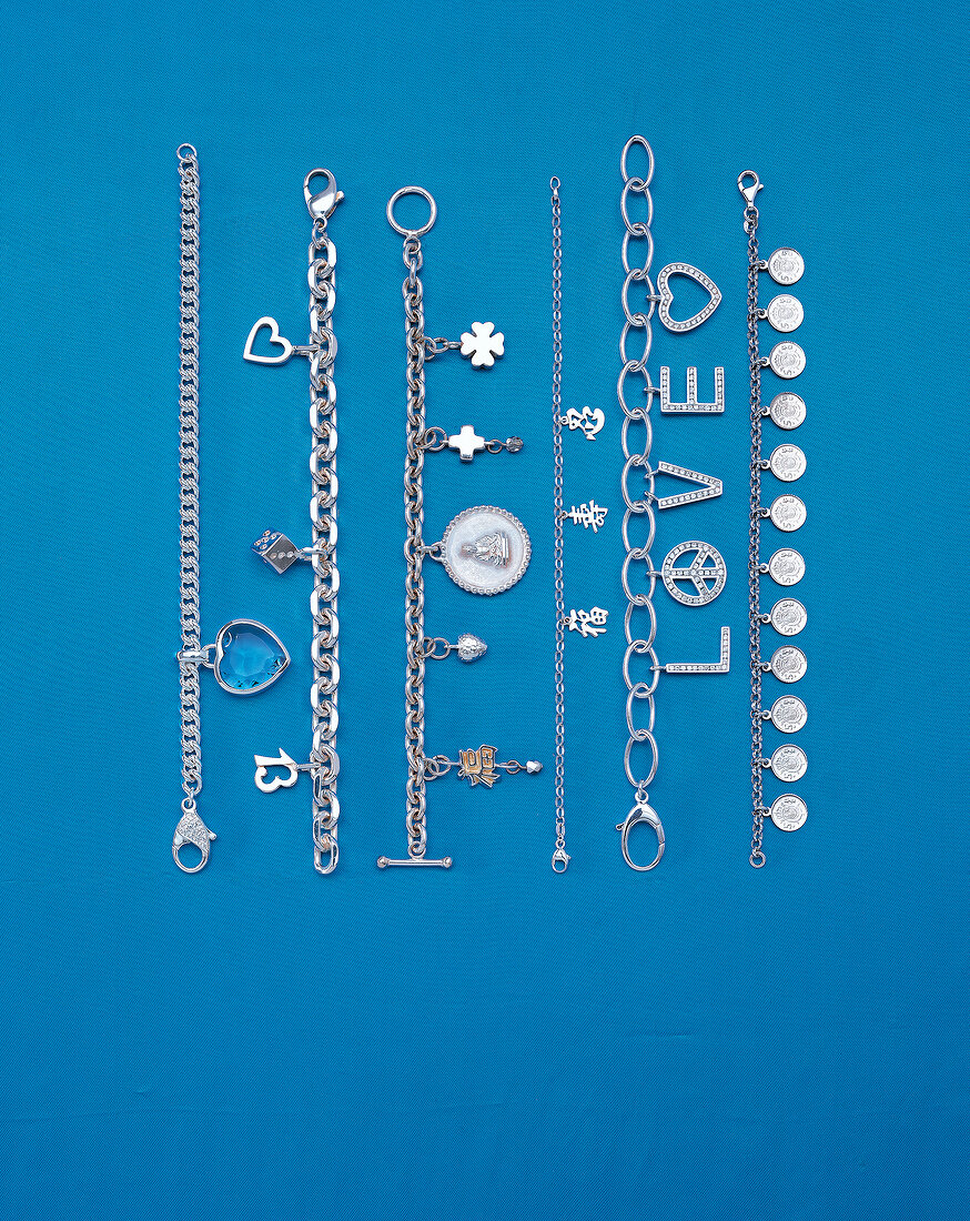 Different types of silver bracelets on blue background