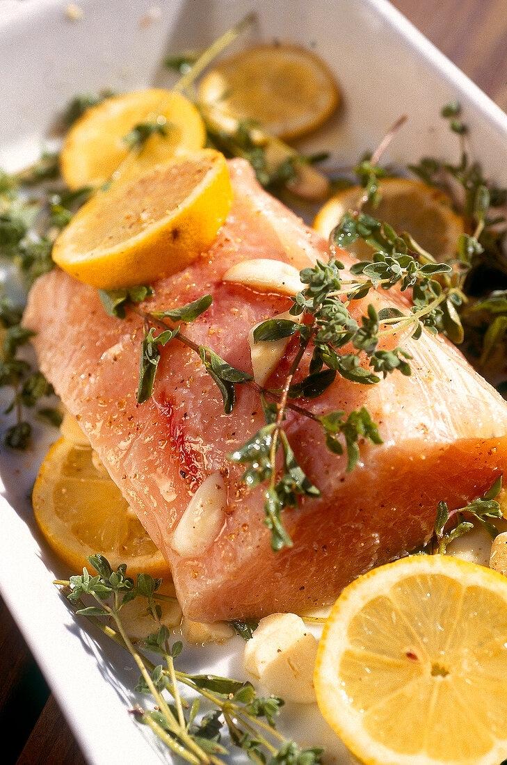 Raw swordfish with marjoram and lemon slices in baking dish