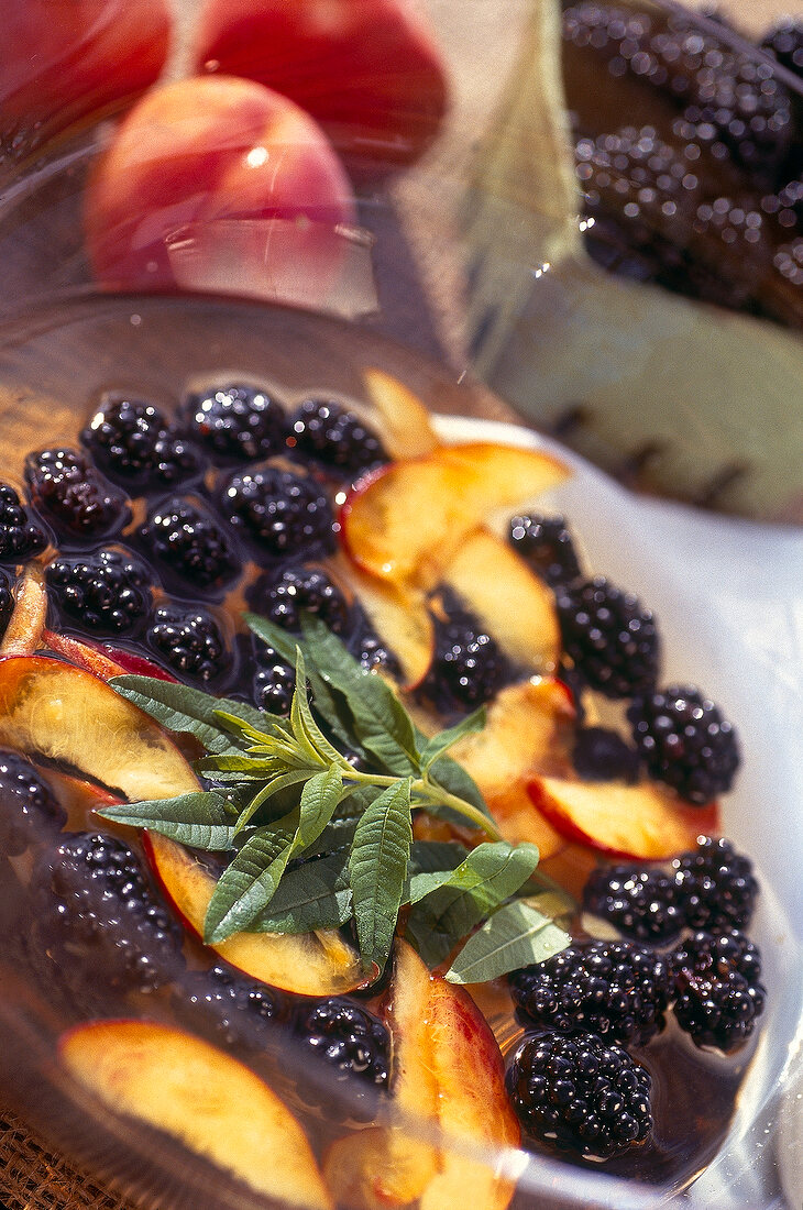 Close-up of peach with lemon verbena and blackberries in bowl