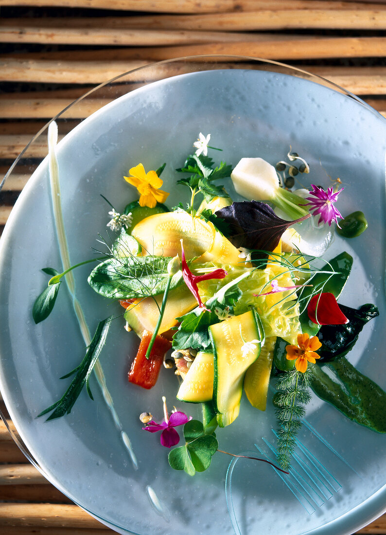 Salad with vegetables and flowers in bowl, overhead view