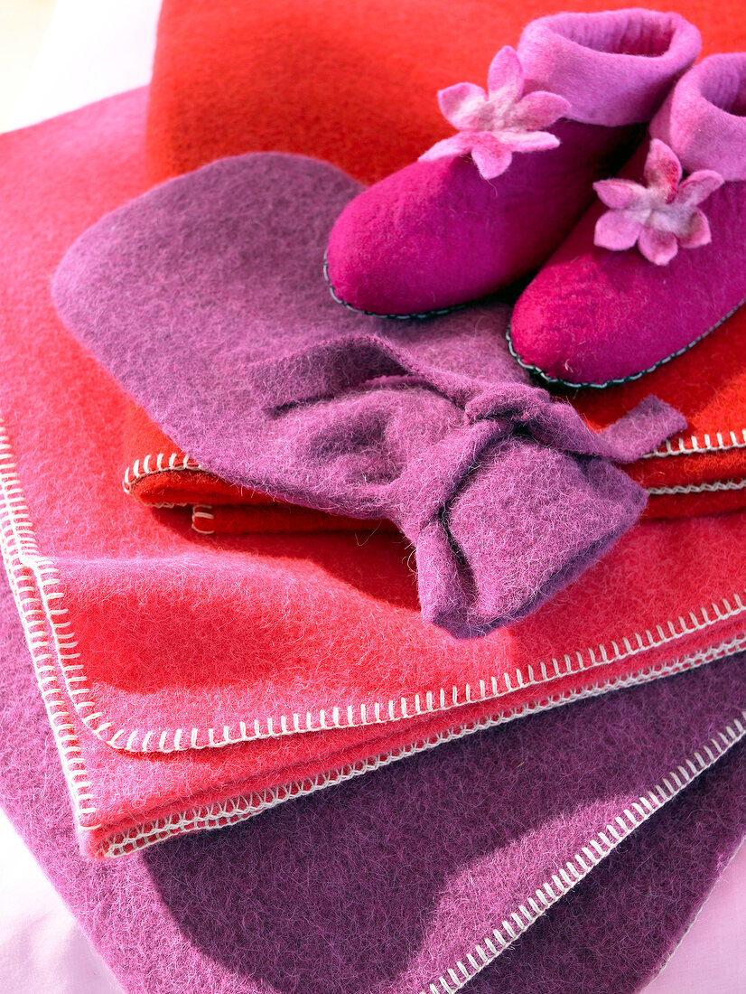 Close-up of colourful stack of woollen blankets with slippers and hot water bag