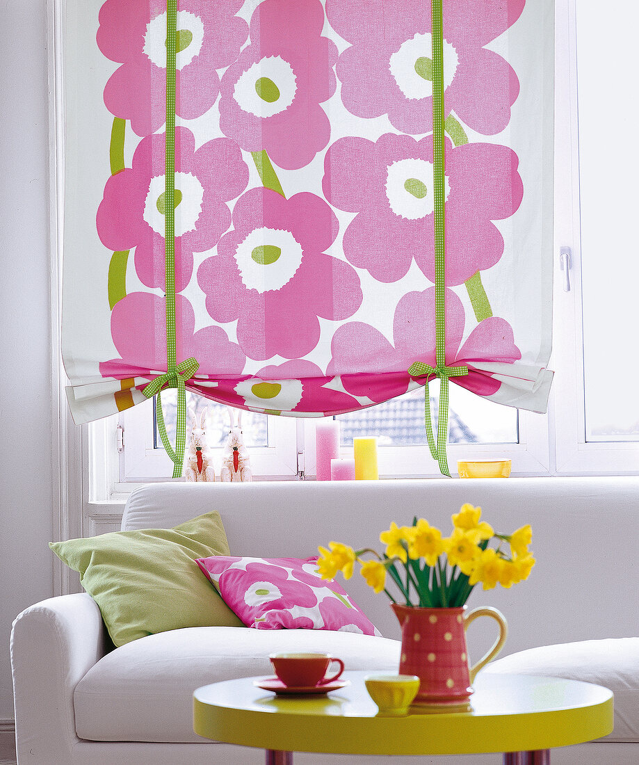 Fenster mit buntem Raffrollo, rosa Blütendruck, grüne Stoffbänder