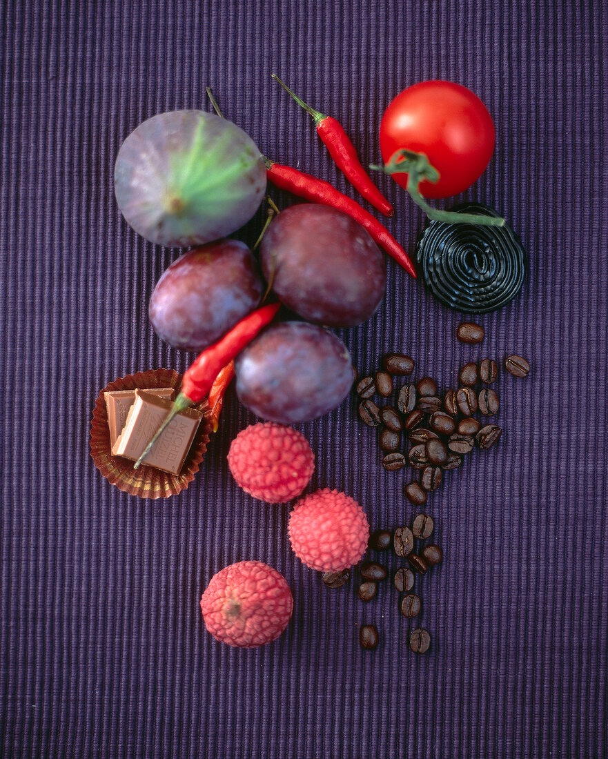 Fruits, vegetables, sweets and coffee beans on purple surface