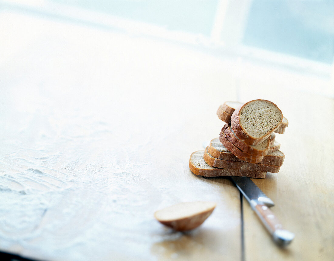 Stack of rye bread slices on a knife on wooden table