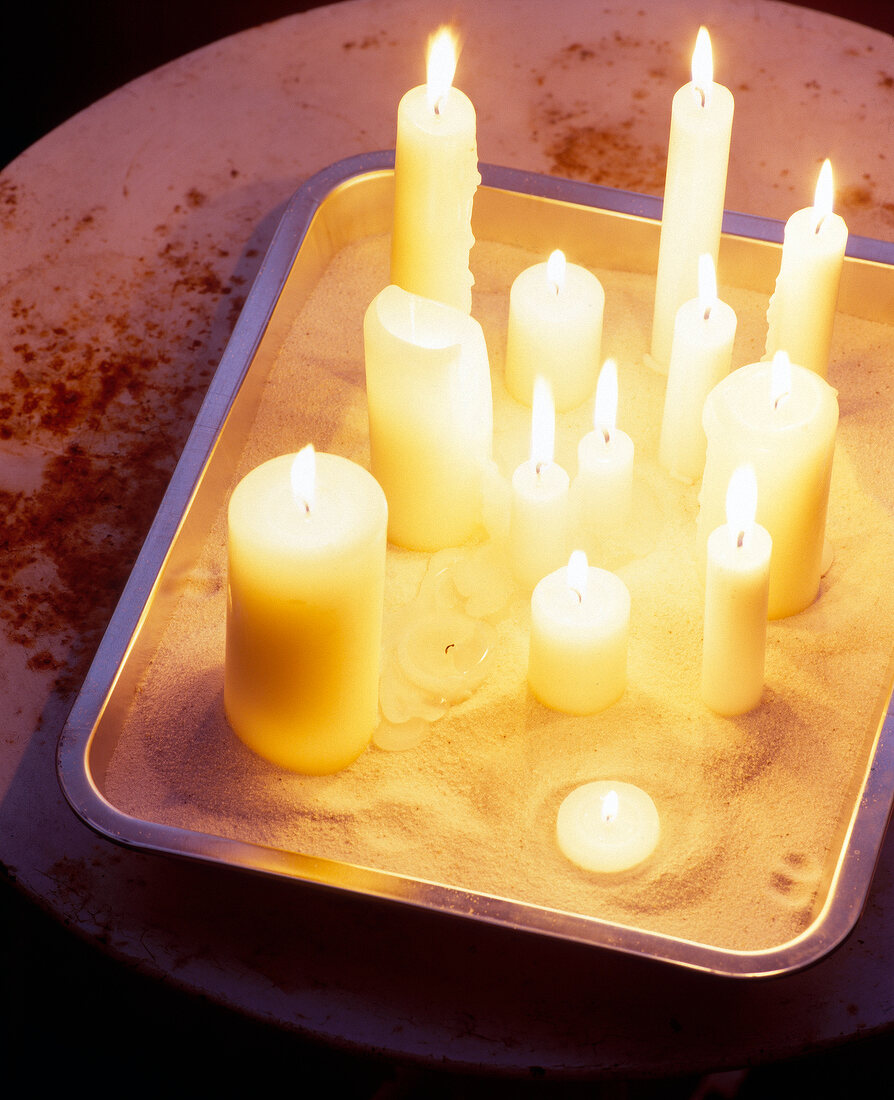Flickering candles sprinkled with bird sand on tray
