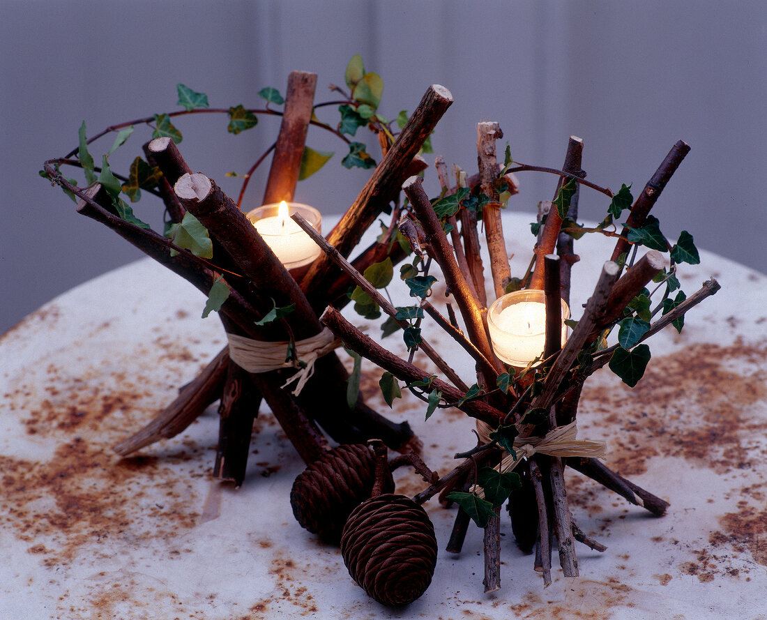 Tea light candle on bundles of branches tied with raffia on rustic table